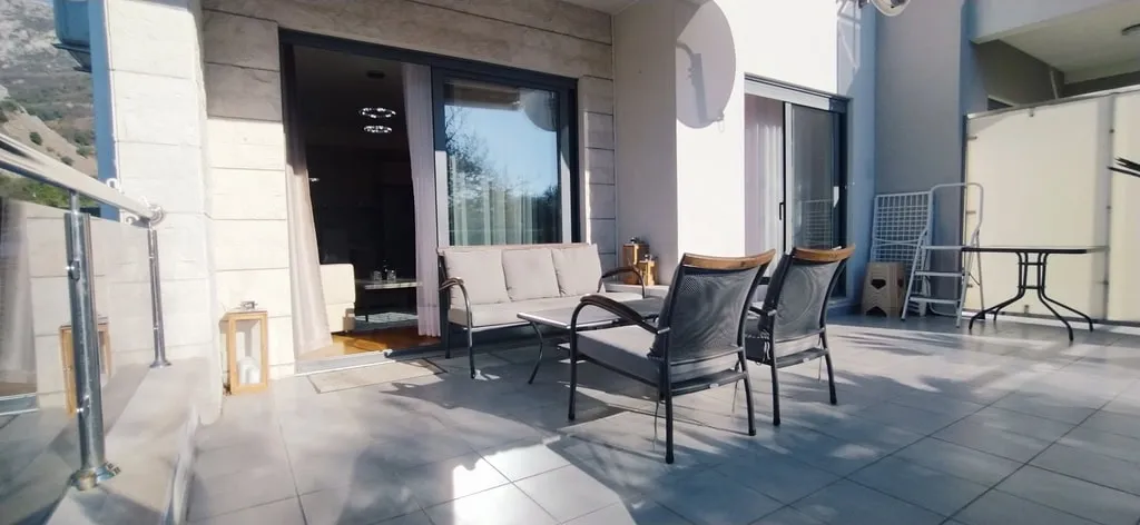 Open terrace with outdoor furniture, glass railing, and a view of the hills.
