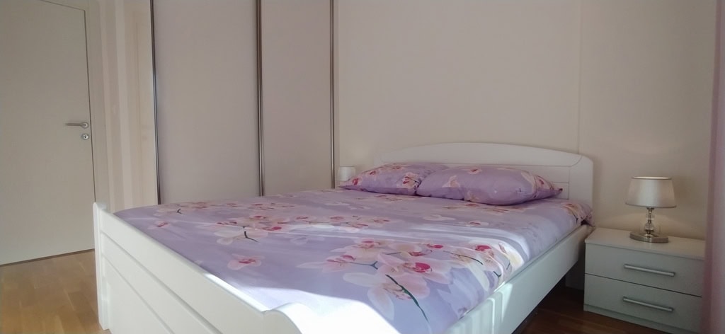 Bright bedroom with a double bed and built-in wardrobe in an apartment in Bečići, Montenegro.