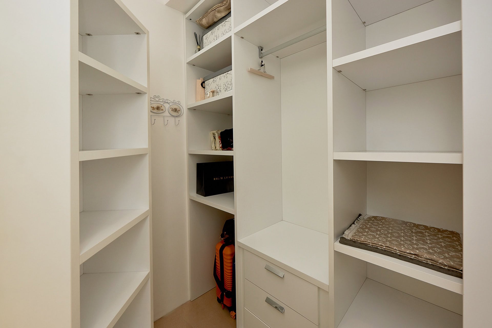 White dressing room with open shelves and pull-out drawers in a penthouse, Bečići, Montenegro.