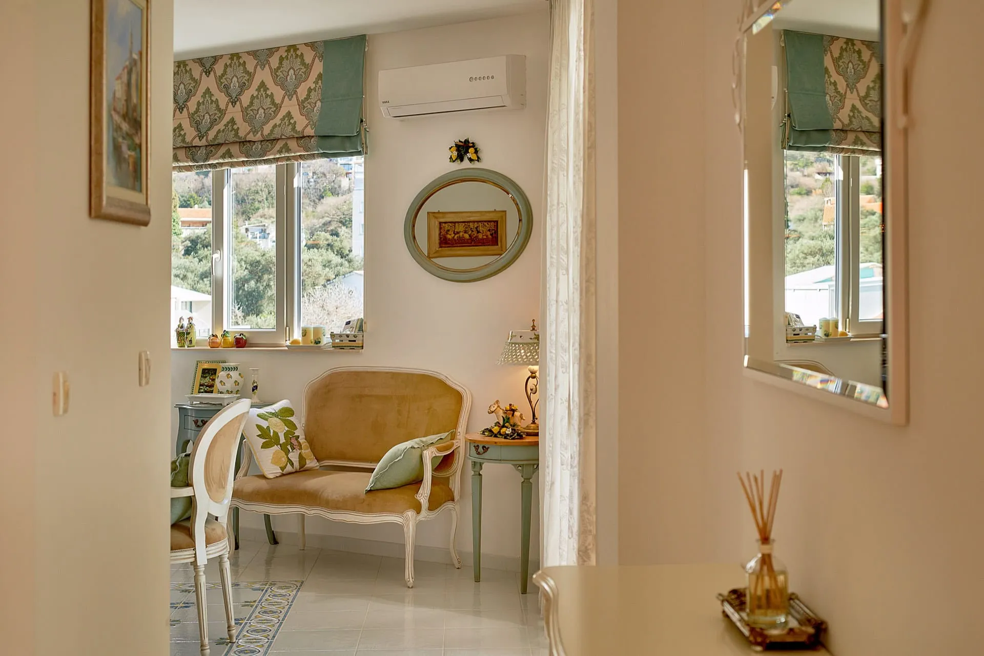 Bright room featuring a vintage settee, oval mirror, and AC unit near the window.