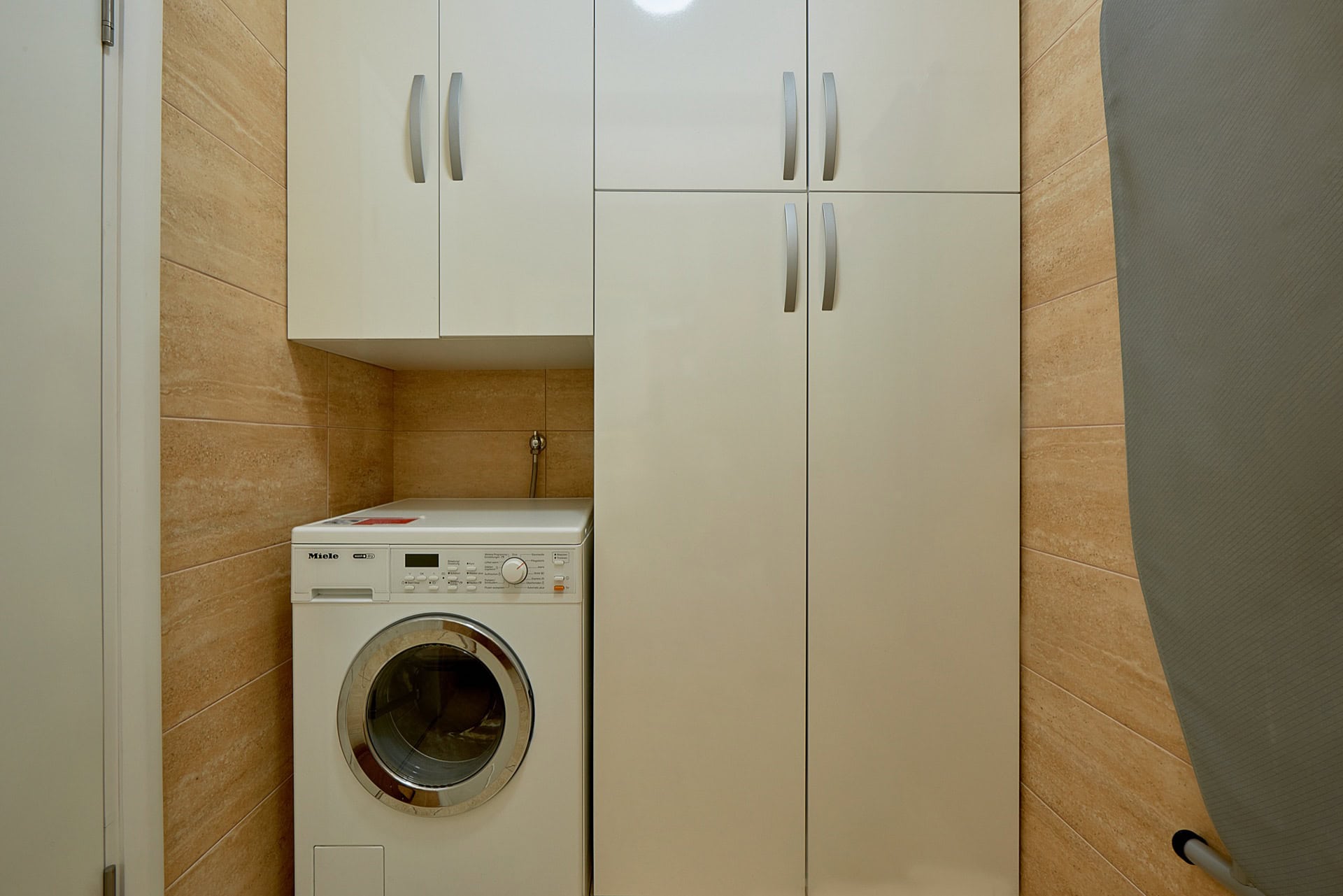 Utility area with a white Miele washing machine and built-in wardrobe in a penthouse, Bečići, Montenegro.
