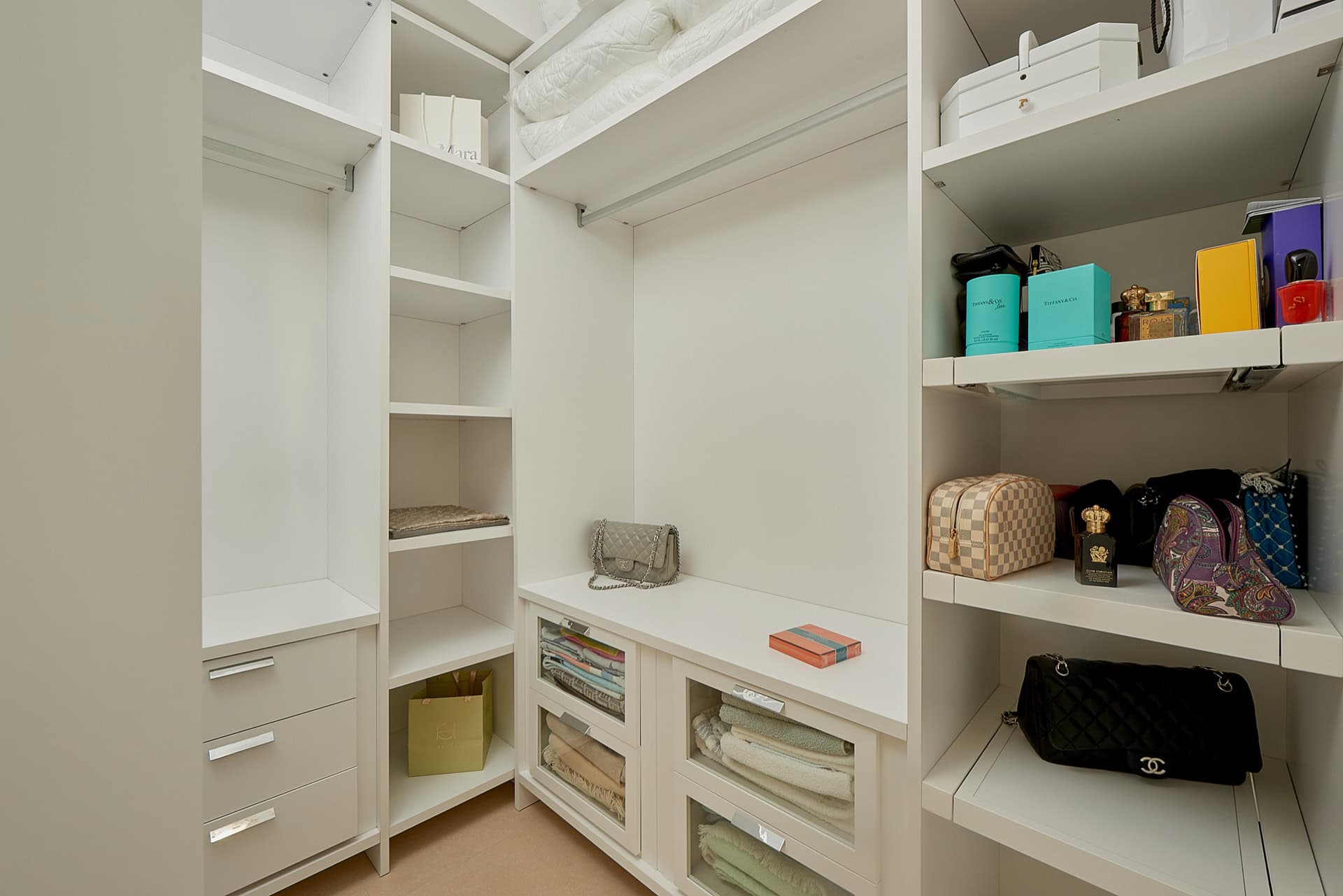White dressing room with shelves and pull-out drawers in a penthouse, Bečići, Montenegro. Modern storage system.