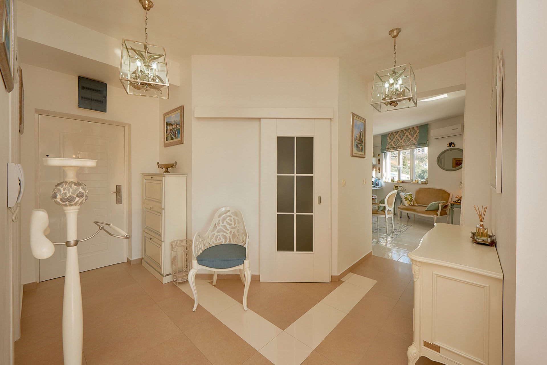Bright hallway and living room in a penthouse in Bečići, Montenegro: classic furniture, sliding doors, and tiles.