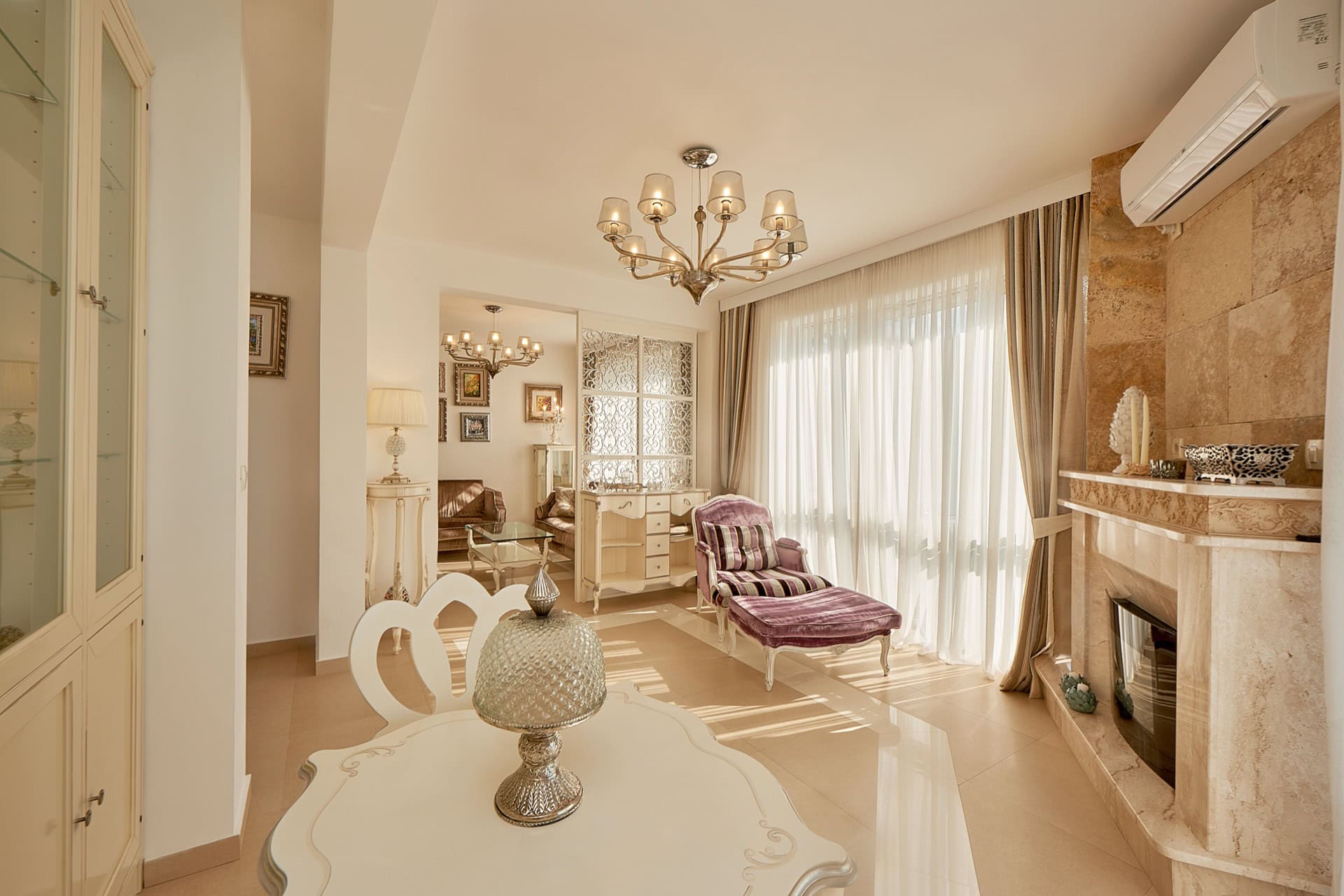 Luxurious living room with a fireplace and classic furniture in a penthouse, Bečići, Montenegro. Bright interior with panoramic windows.