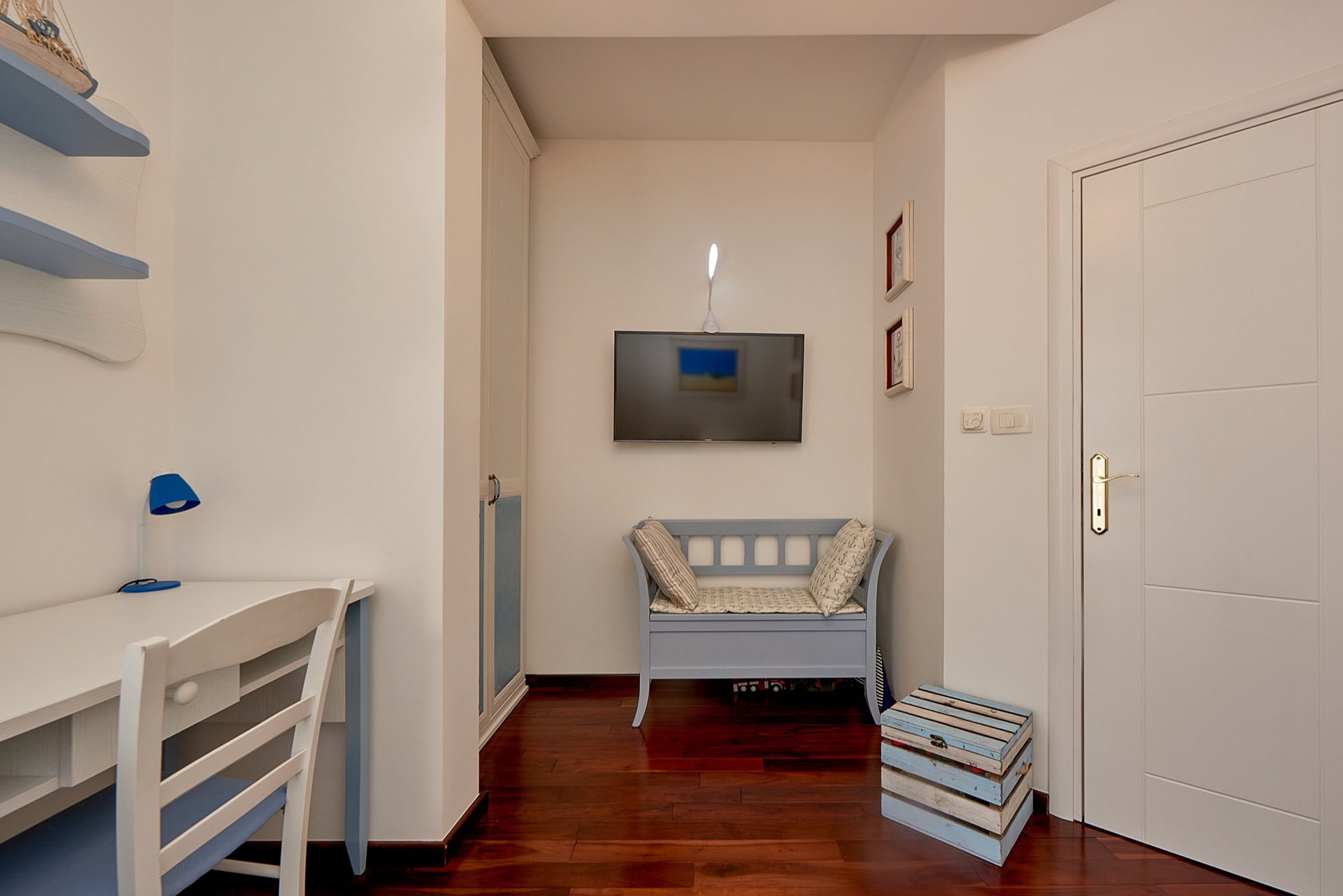 Interior of a living room in a penthouse in Bečići, Montenegro: light-colored furniture, TV, workspace, and parquet flooring.