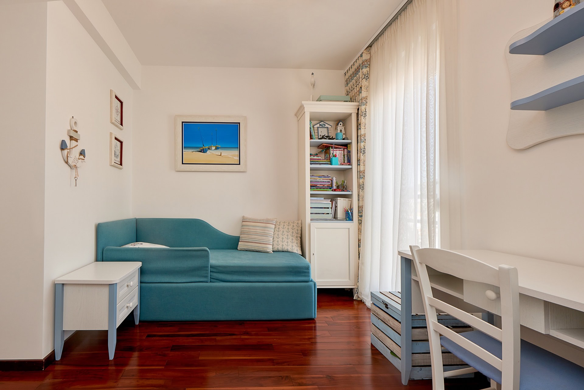 Children's bedroom in a nautical style in a penthouse, Bečići, Montenegro: blue sofa, desk, and parquet flooring.