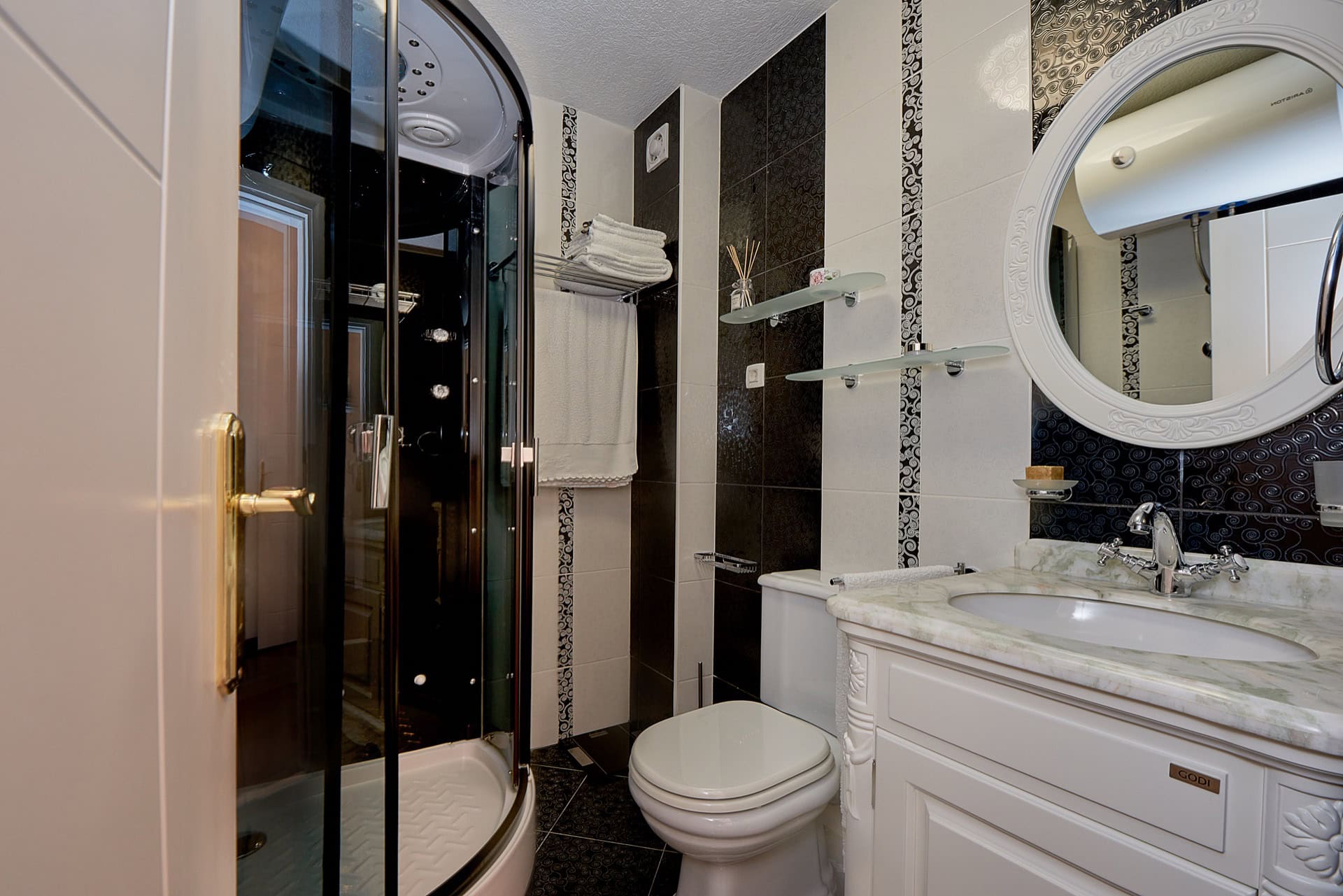 Bathroom in a penthouse in Bečići, Montenegro: shower cabin, vanity unit with marble countertop, and round mirror.