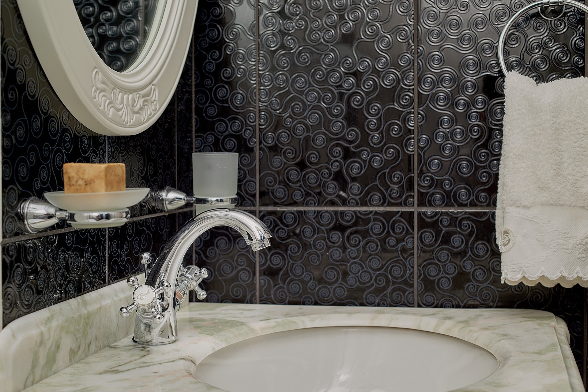 Bathroom in a penthouse in Bečići, Montenegro: marble countertop, chrome faucet, and black tiles.
