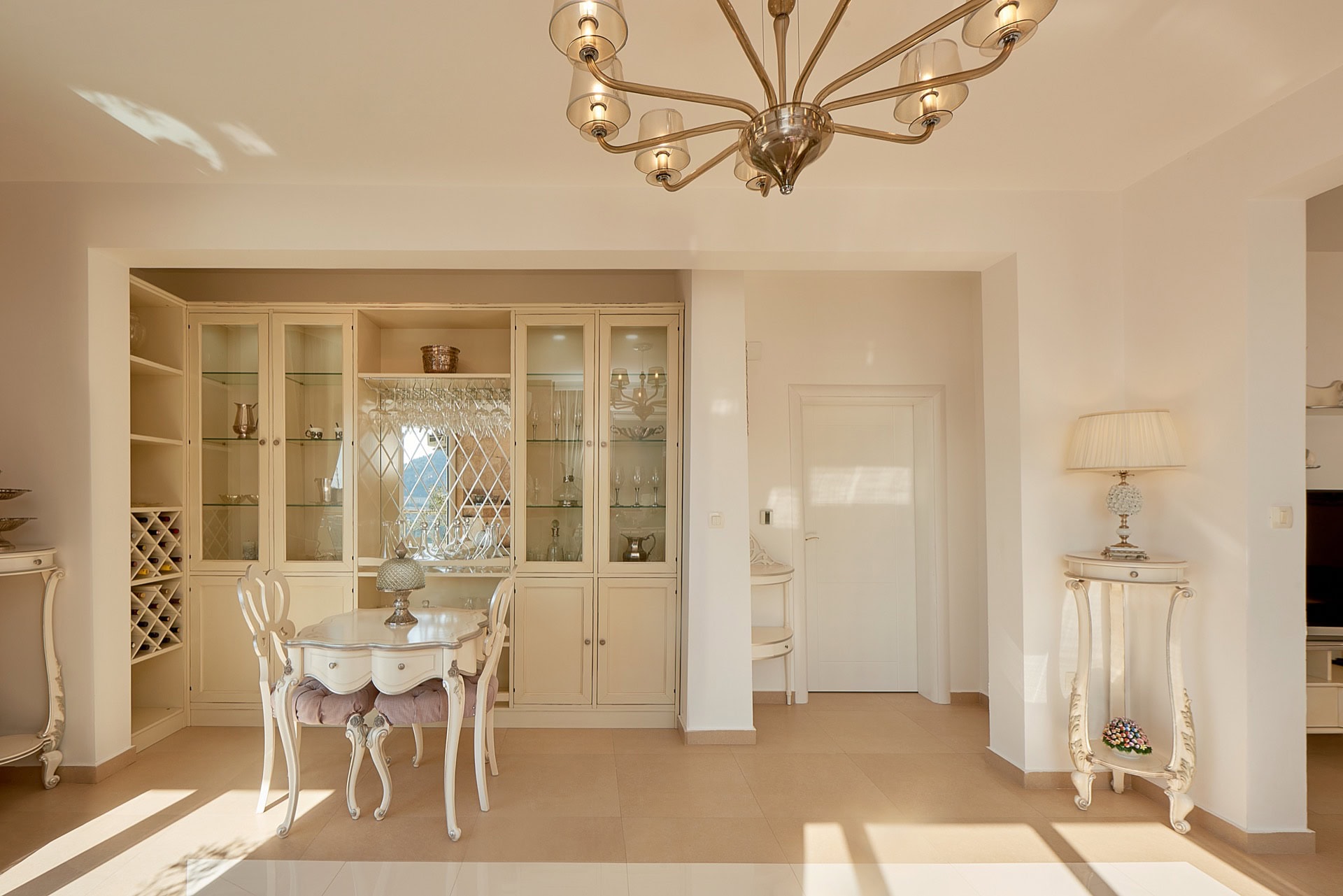 Classic-style living room in a penthouse, Bečići, Montenegro: light-colored furniture, a display cabinet for dishes, and a chandelier.