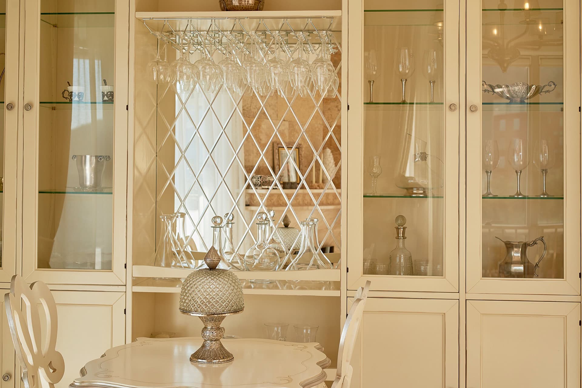 Classic light-colored sideboard with a display cabinet and glasses in the interior of a penthouse in Bečići, Montenegro.