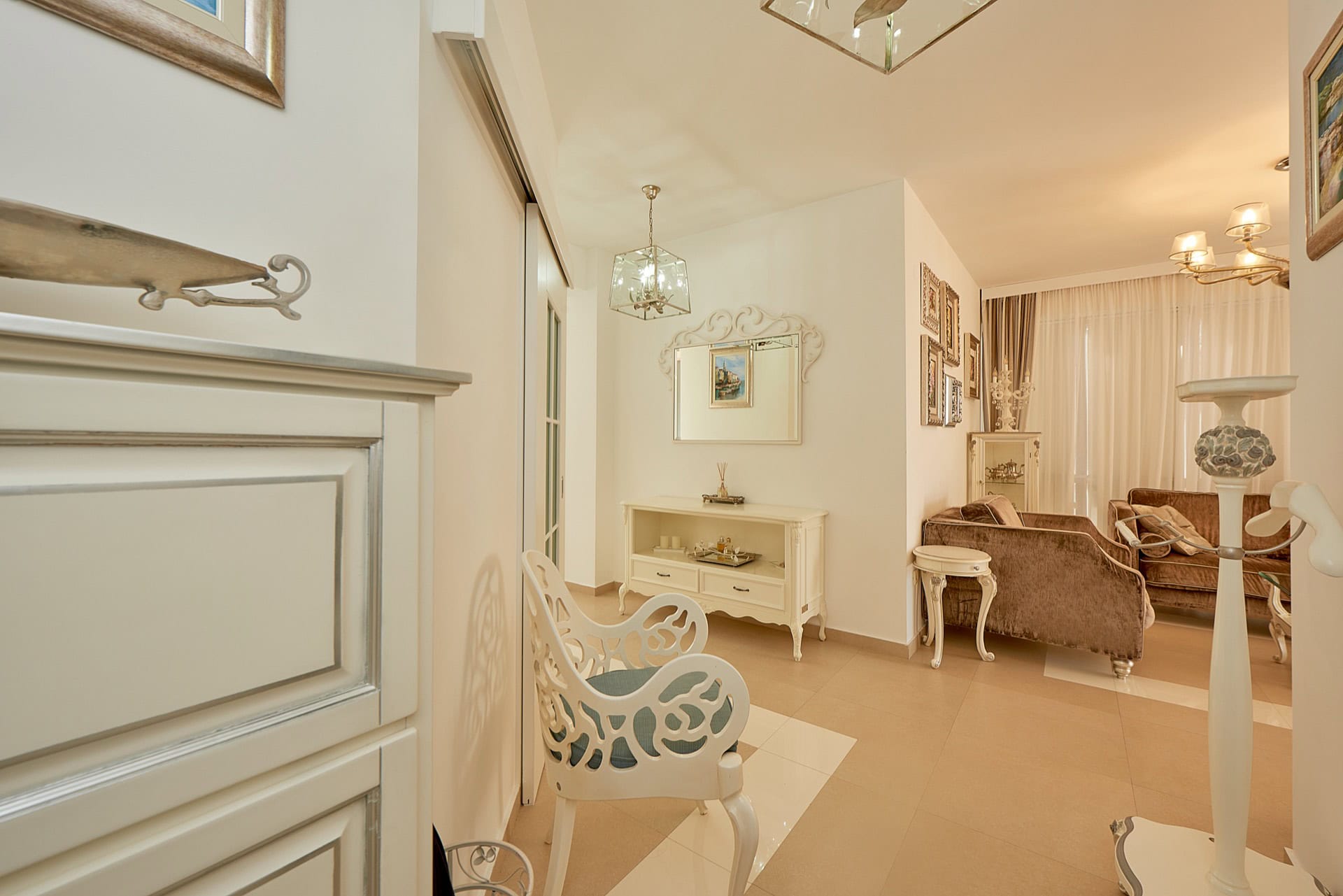 Bright living room in a classic style in a penthouse, Bečići, Montenegro: white furniture, cozy sofa, and decor.