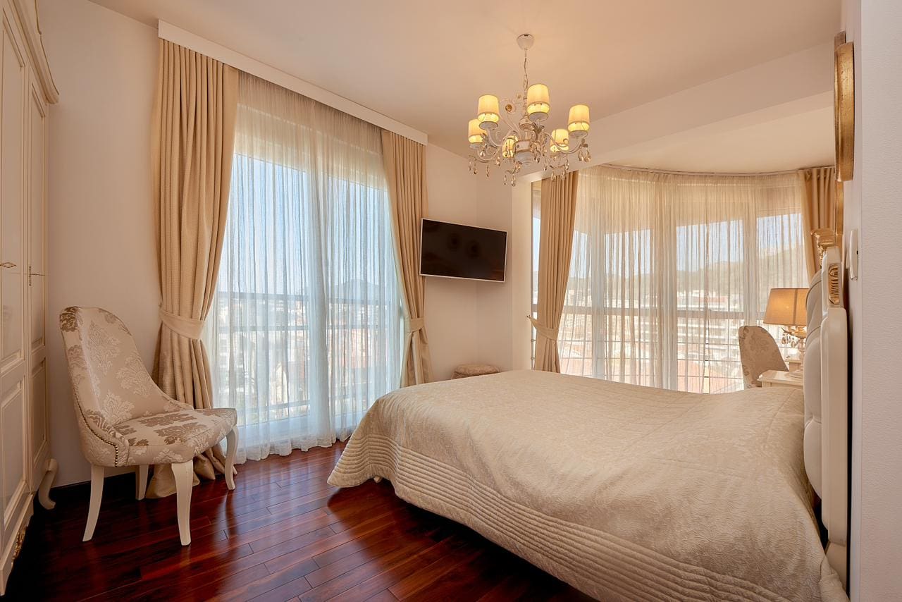 Cozy bedroom with a double bed and panoramic windows in a penthouse, Bečići, Montenegro.