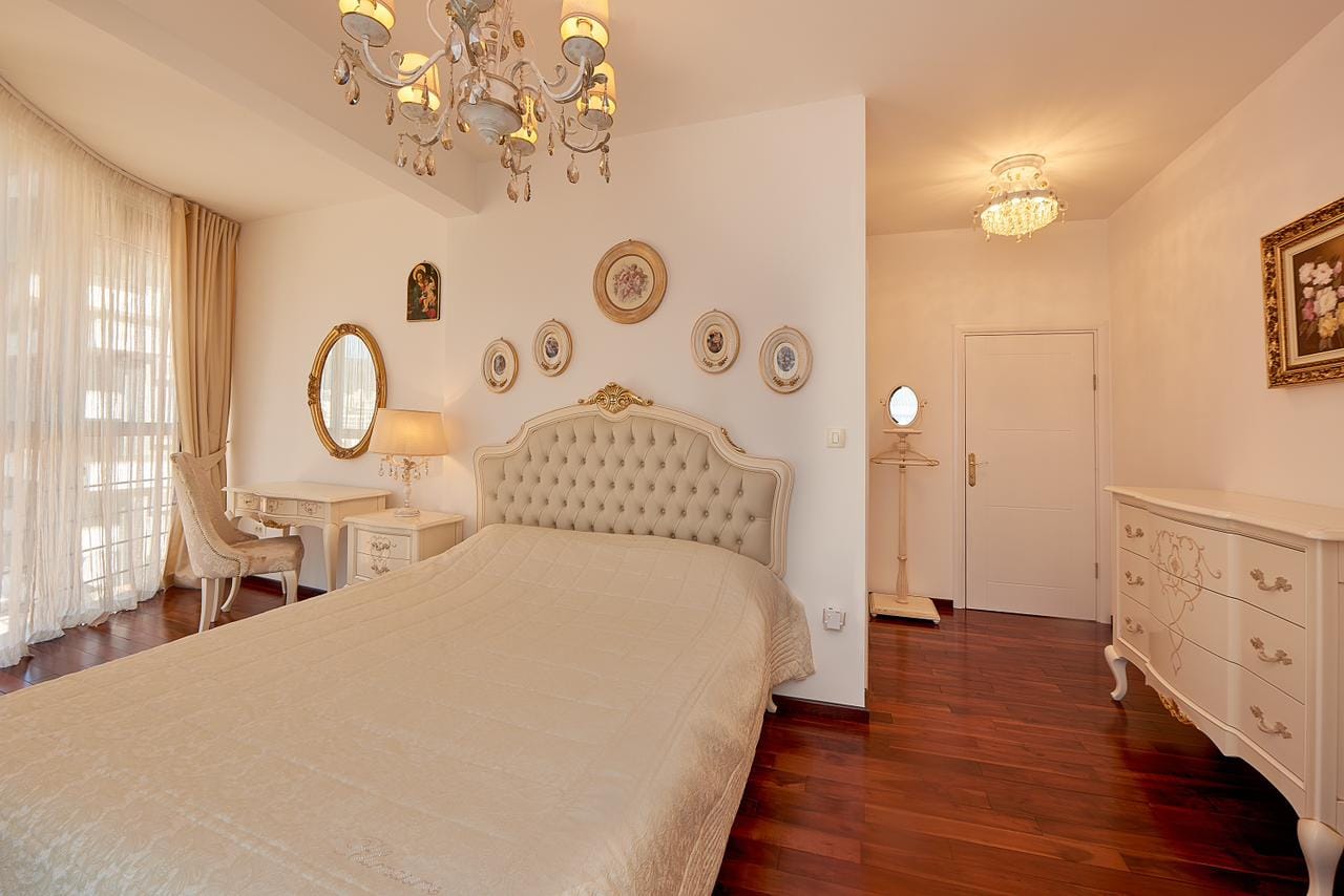 Bright bedroom in classic style in a penthouse, Bečići, Montenegro: double bed, dresser, and parquet floor.