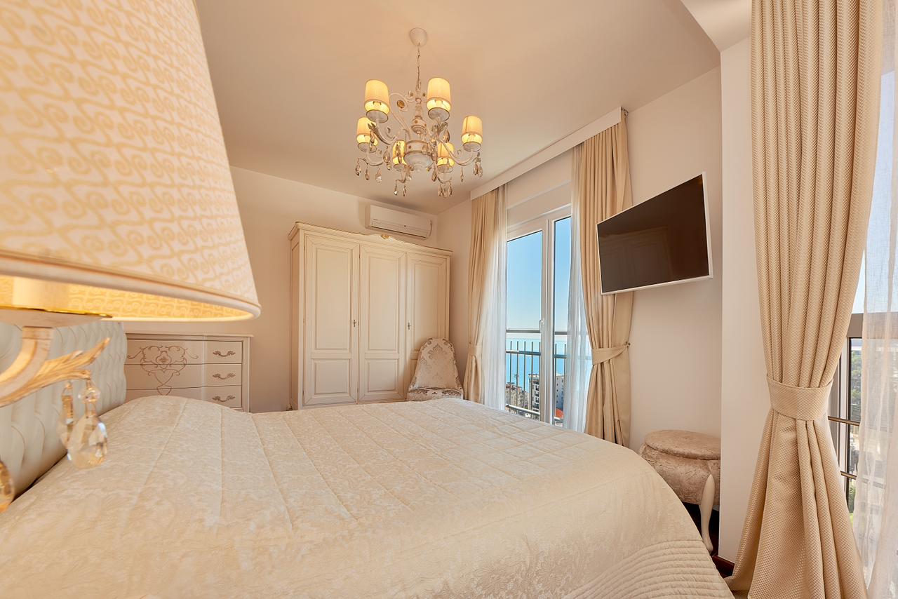 Bright bedroom in a penthouse in Bečići, Montenegro: double bed, classic furniture, and sea view from the balcony.