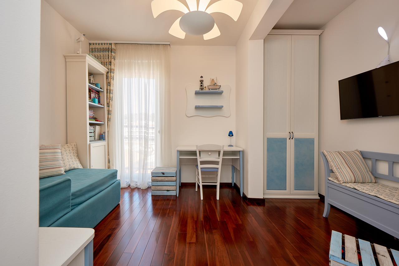 Bright bedroom in a marine style in a penthouse, Bečići, Montenegro: wooden floor, built-in wardrobe, and a workspace.