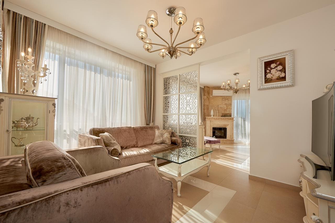 Living room in a penthouse in Bečići, Montenegro: classic interior, upholstered furniture, decorative partition, and fireplace.