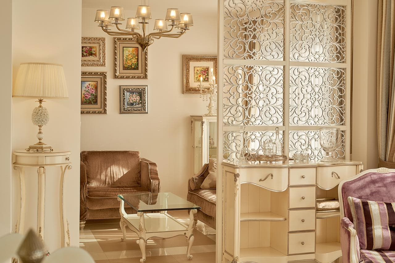 Interior of a classic-style penthouse living room in Bečići, Montenegro: carved partition, vintage furniture and decor.