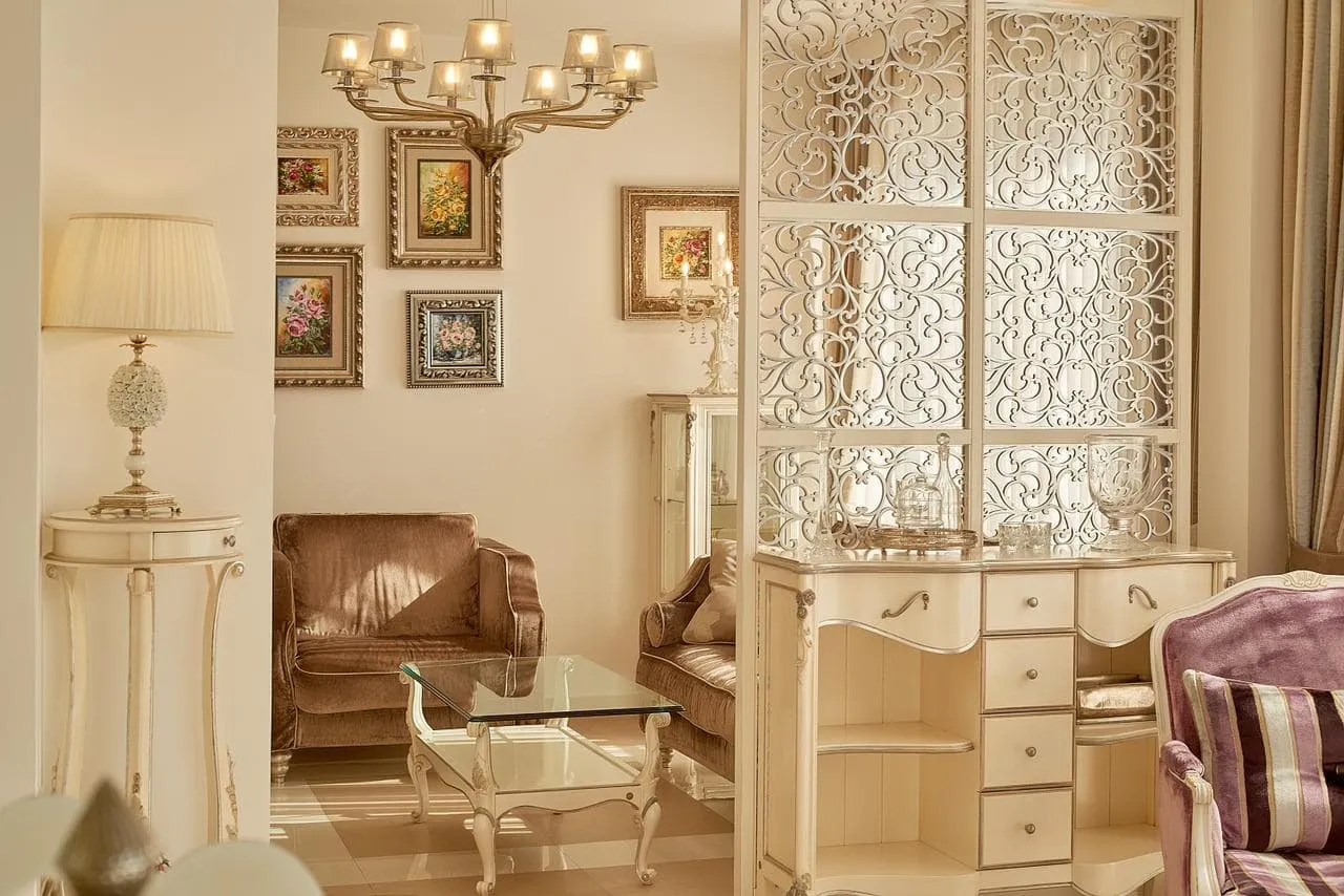Classic living room featuring a velvet sofa, glass coffee table, chandelier, and ornate white screen.