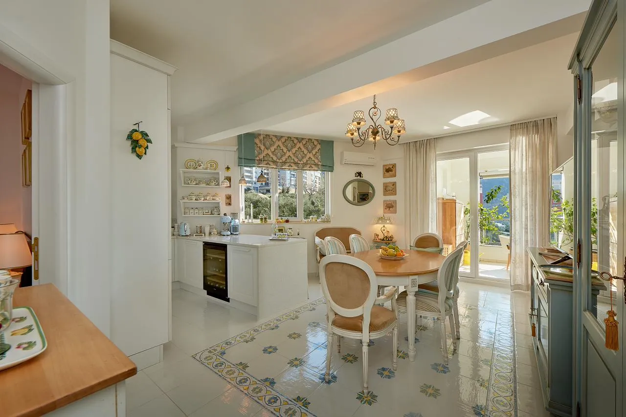 Kitchen with dining area, white cabinets, island, and patterned tile floor.