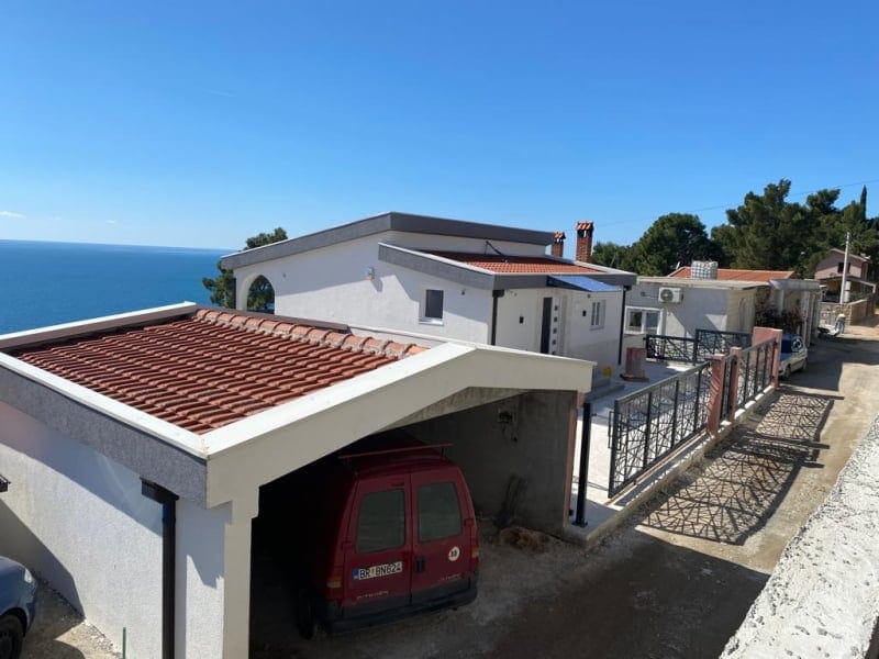 White house with a tiled roof, carport, and panoramic sea view in Shushan, Montenegro.
