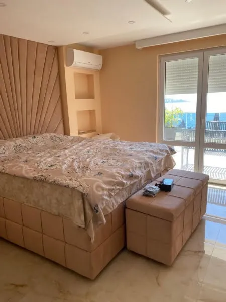 Bedroom featuring a large upholstered bed, beige fan-headboard, and matching bench at the foot.
