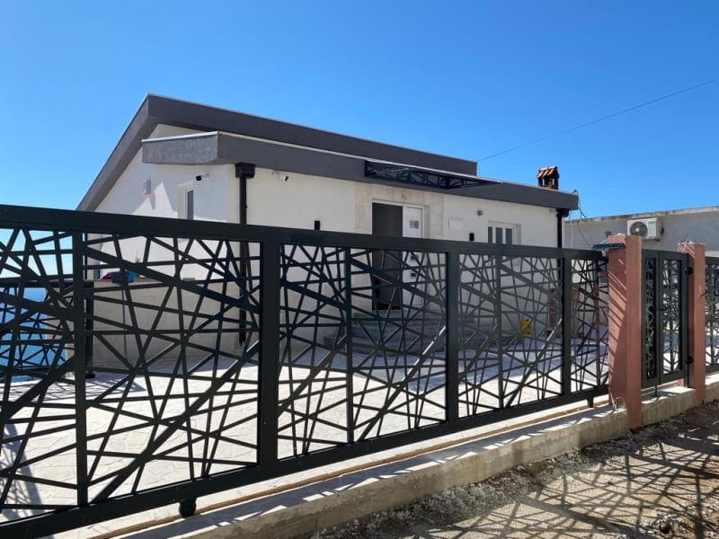 Modern single-story house in Shushan, Montenegro, with designer wrought-iron gates and a paved courtyard.