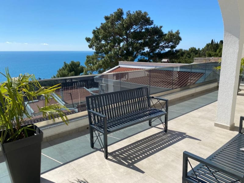 Spacious terrace with sea view in a house, Shushan, Montenegro: metal furniture and glass railing.