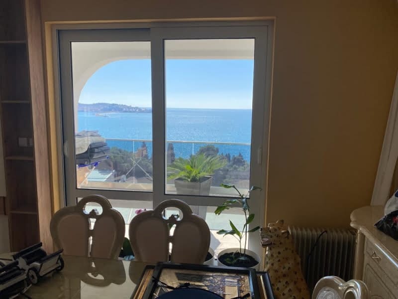 Dining area with decorative chairs and a large window overlooking the sea.