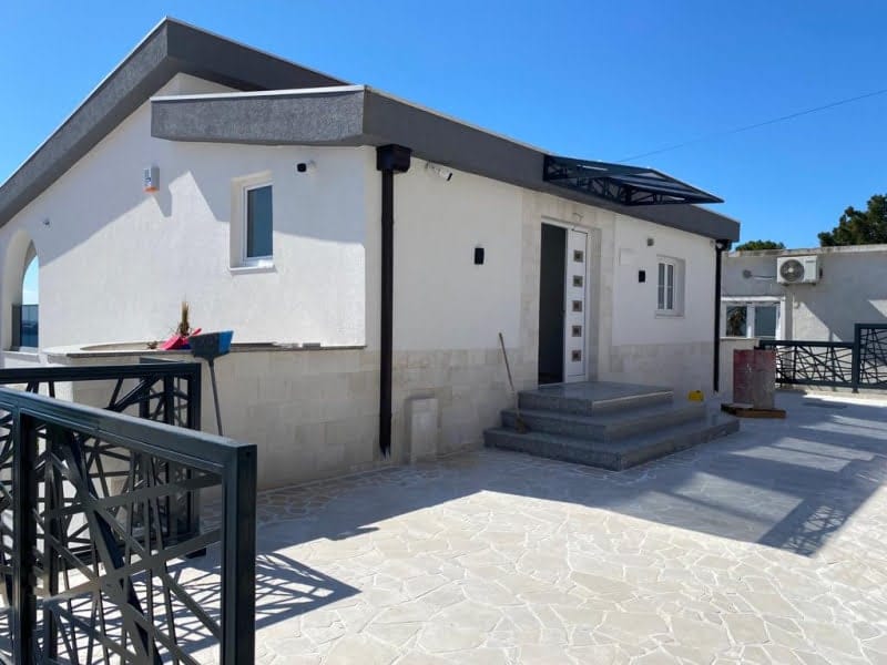 Modern single-story house in Shushan, Montenegro: stone-clad facade, terrace, and entrance area with stairs.