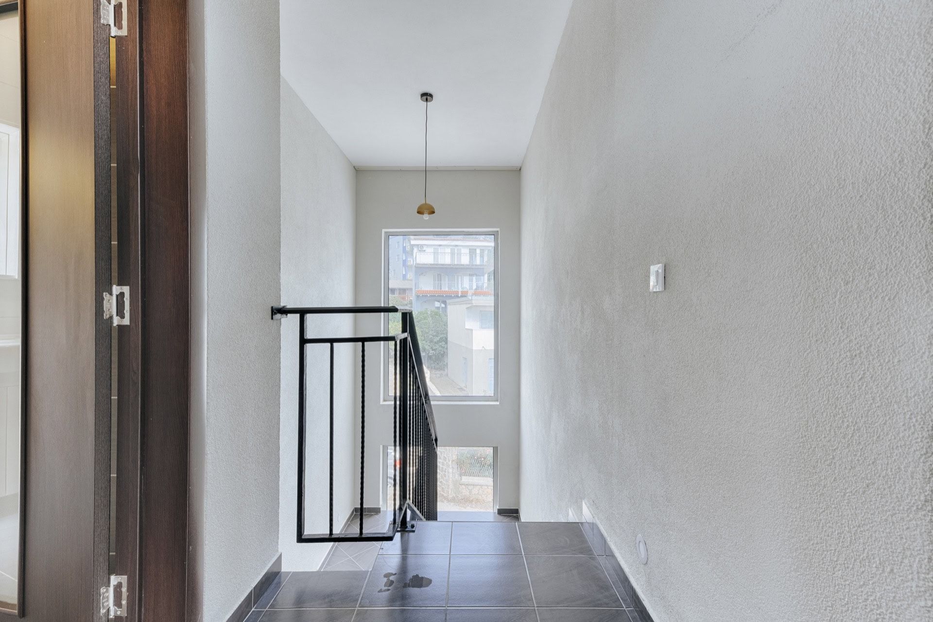Modern staircase with black railings in a villa, Utjeha, Montenegro, light walls and tiled floor.