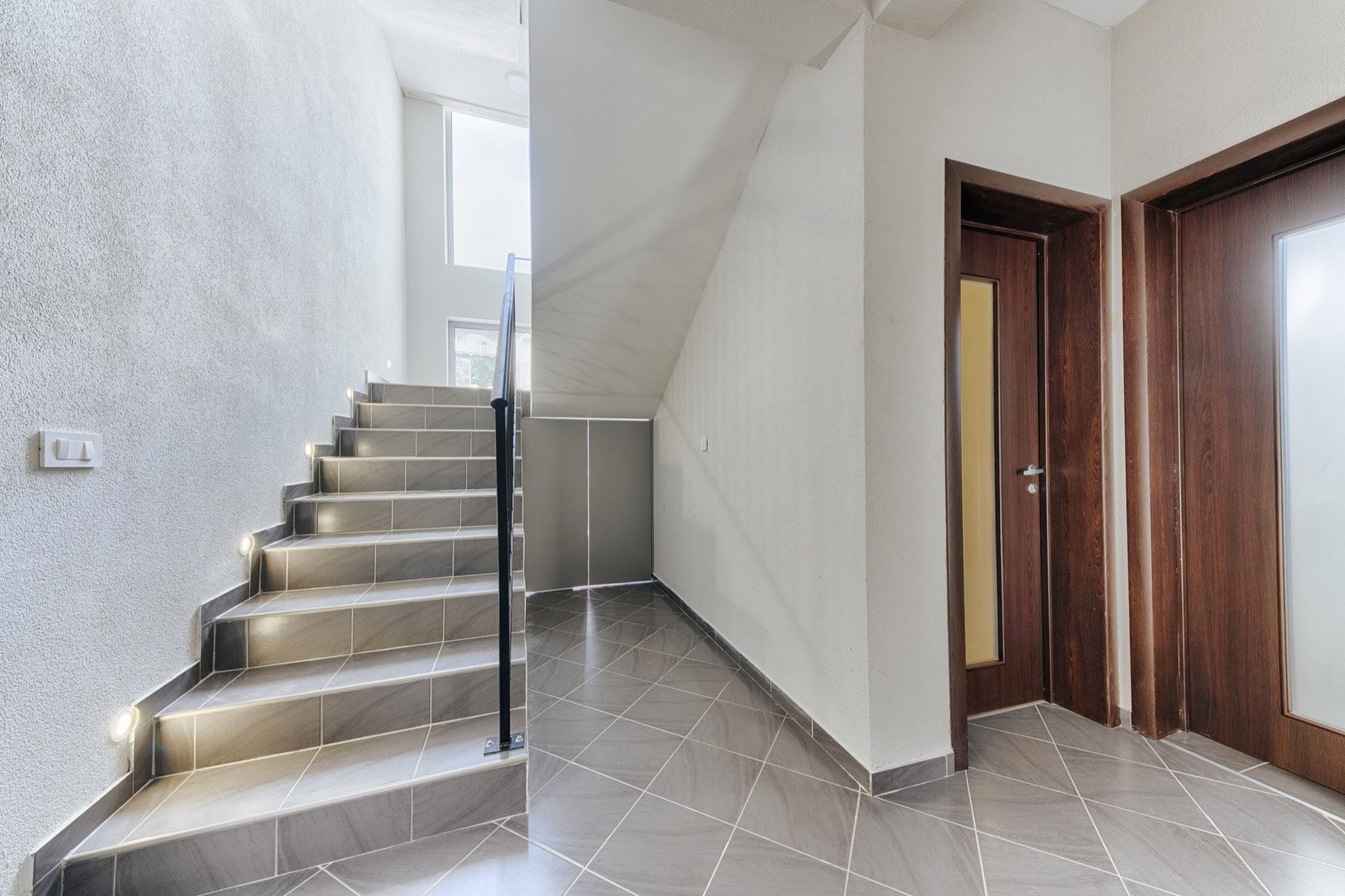 Staircase with step lighting and dark doors in a modern villa, Utjeha, Montenegro. Interior with tile.