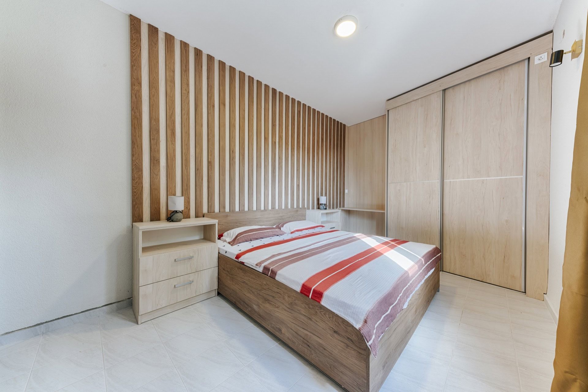 Bedroom with a double bed and wooden slats on the wall in a villa in Utjeha, Montenegro.