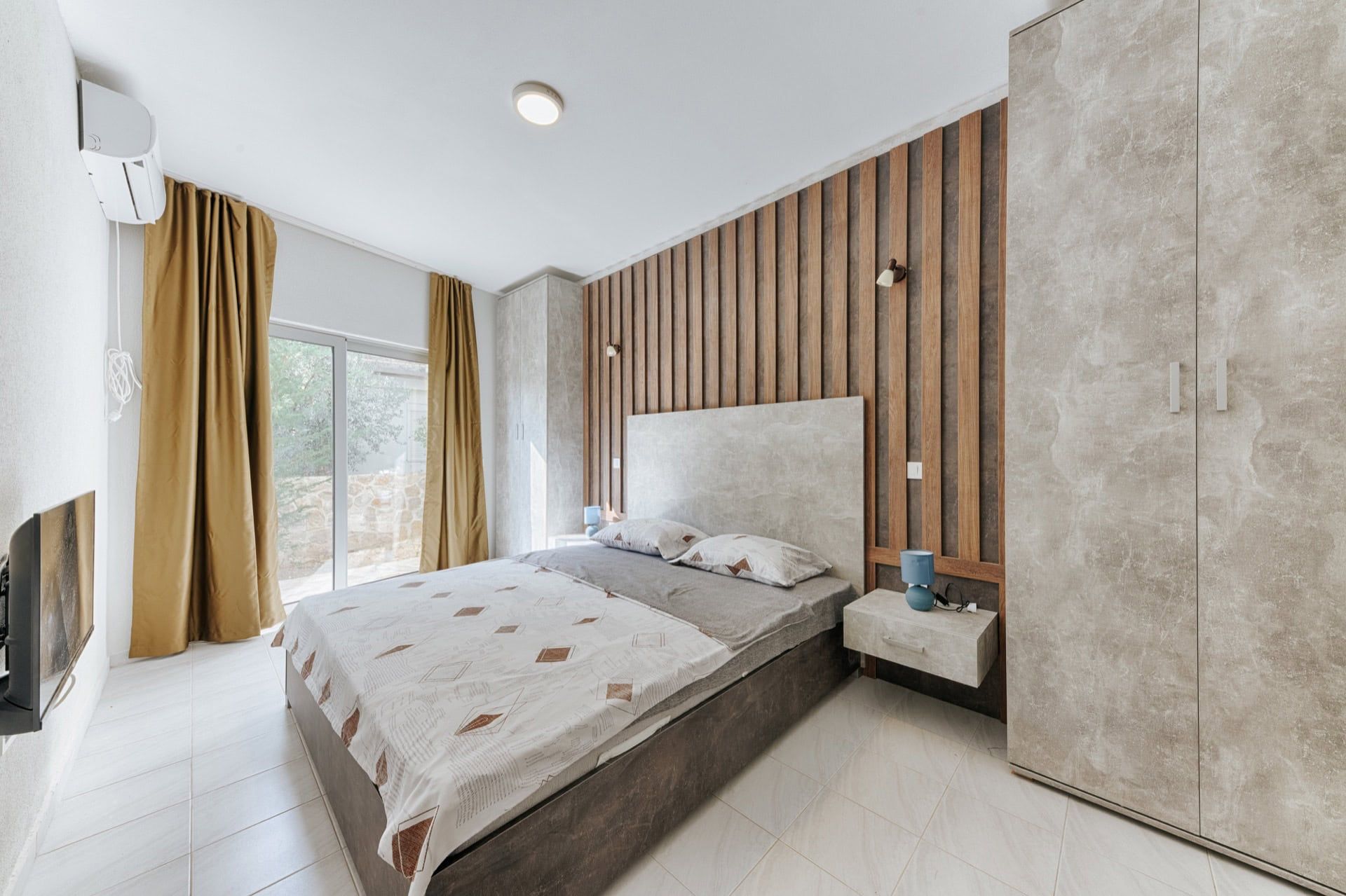 Modern bedroom with a double bed and slatted wall paneling in a villa in Utjeha, Montenegro.
