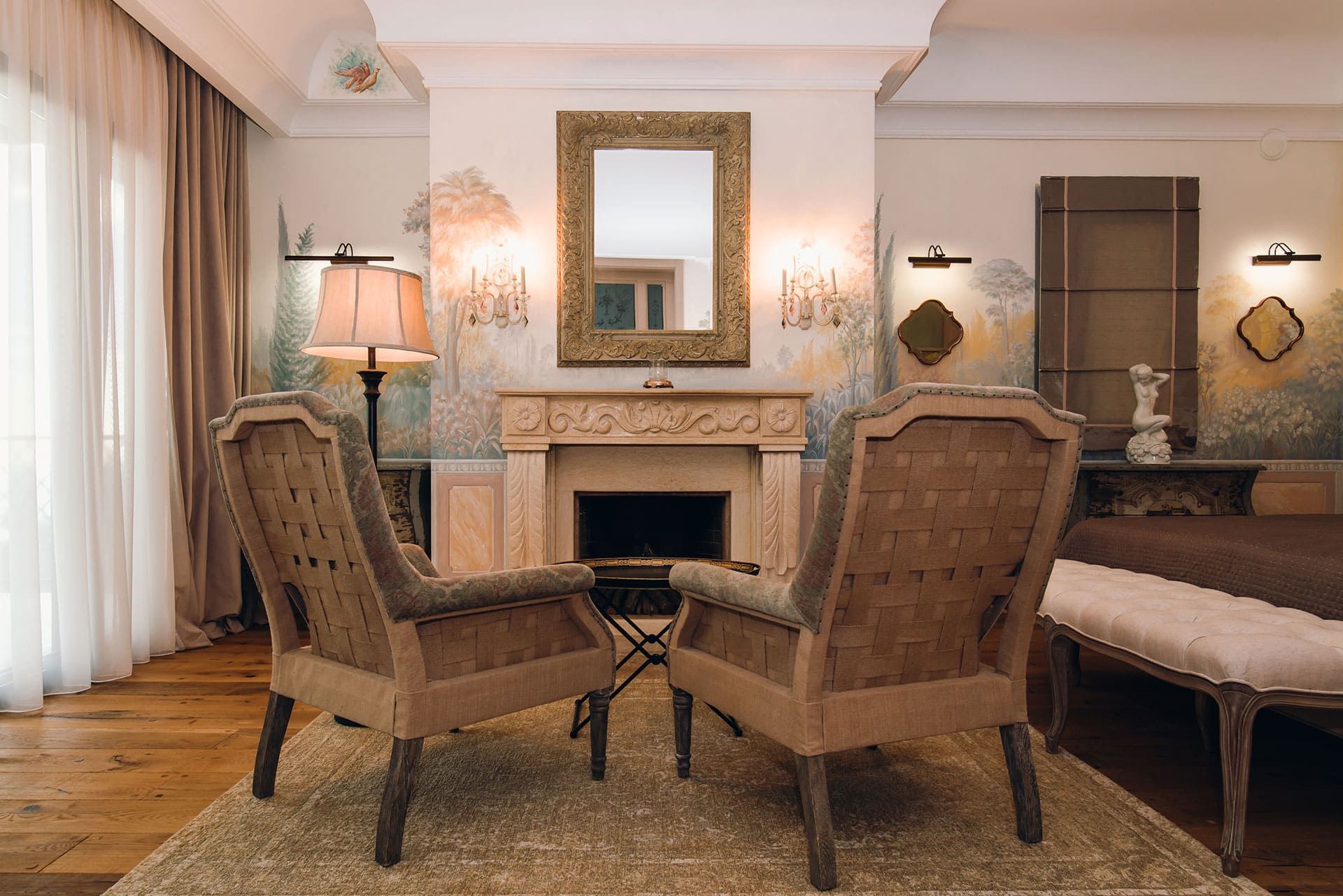 Villa living room in Reževići, Montenegro: fireplace, classic armchairs, wall painting, and a mirror in a gold frame.