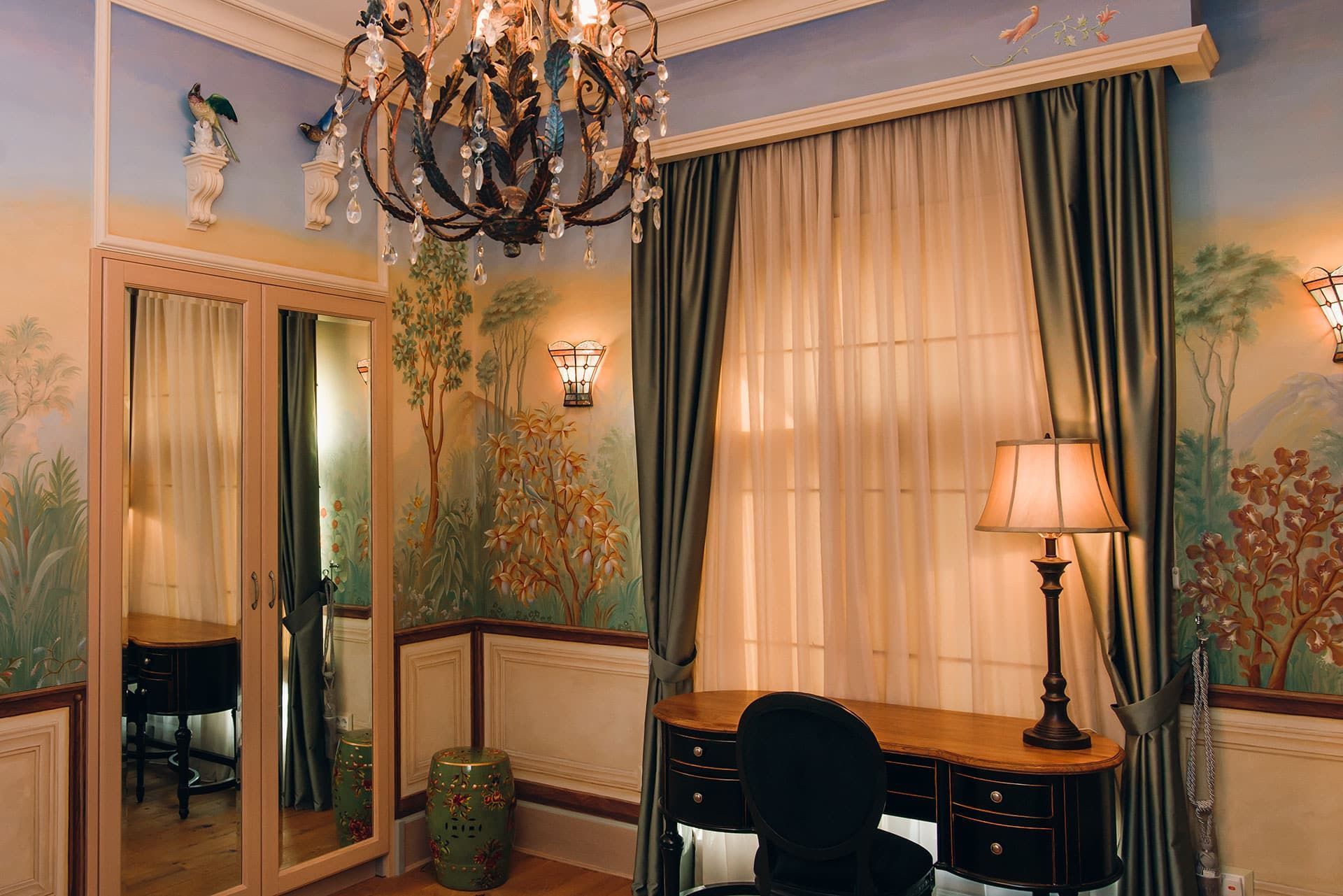 Bedroom in a villa in Rezevici, Montenegro: classic interior with hand-painted walls, a chandelier, and a desk.