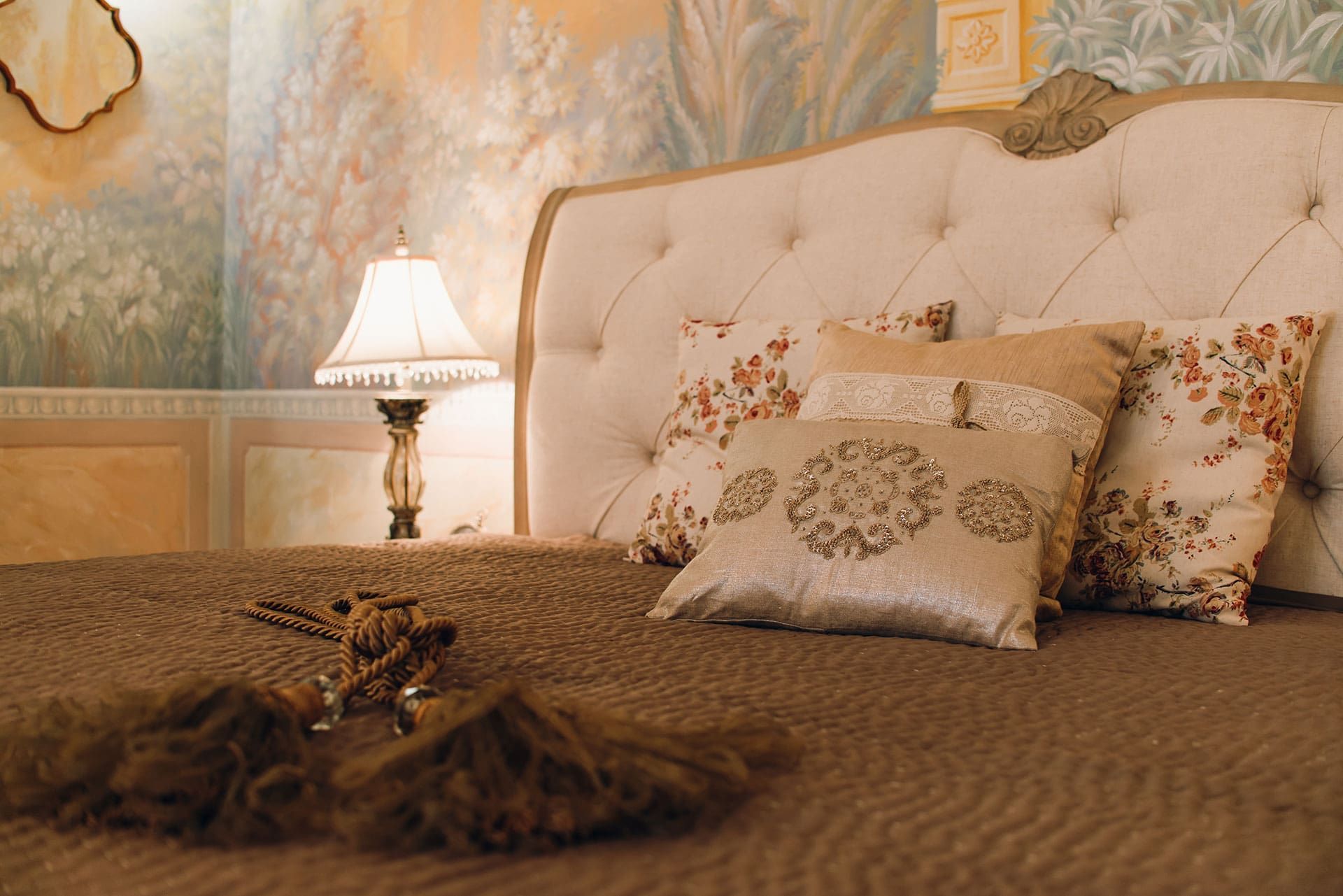 Bedroom interior in a villa in Reževići, Montenegro: bed with a padded headboard, decorative pillows, and wall painting.