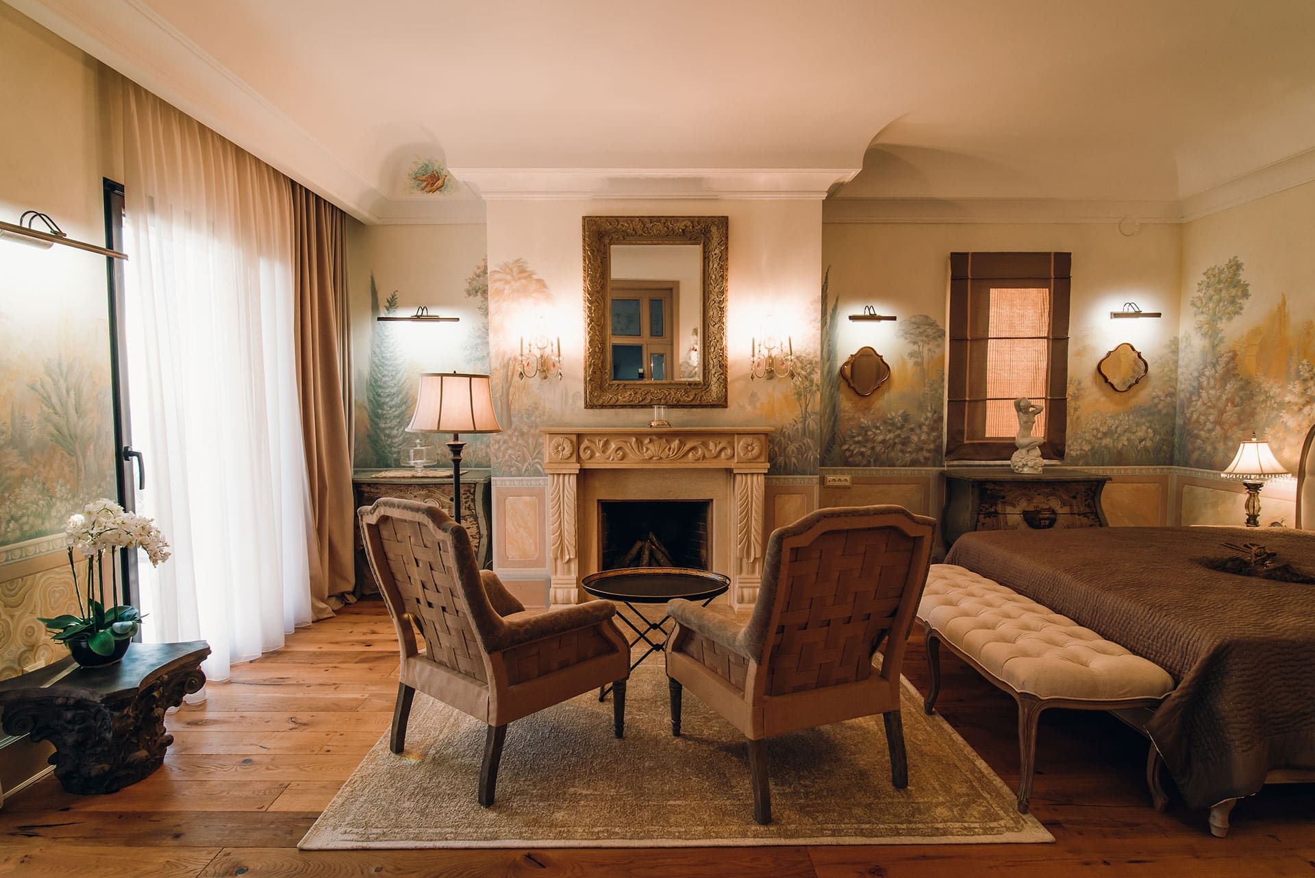 Luxurious bedroom with a fireplace and custom wall painting in a villa in Reževići, Montenegro: classic furniture and decor.