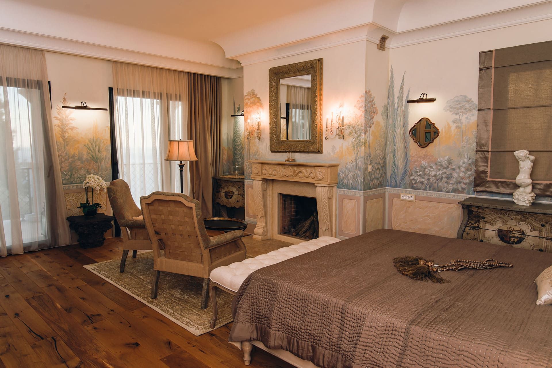Luxurious bedroom with a fireplace and artistic wall painting in a villa in Reževići, Montenegro. Sea and terrace view.