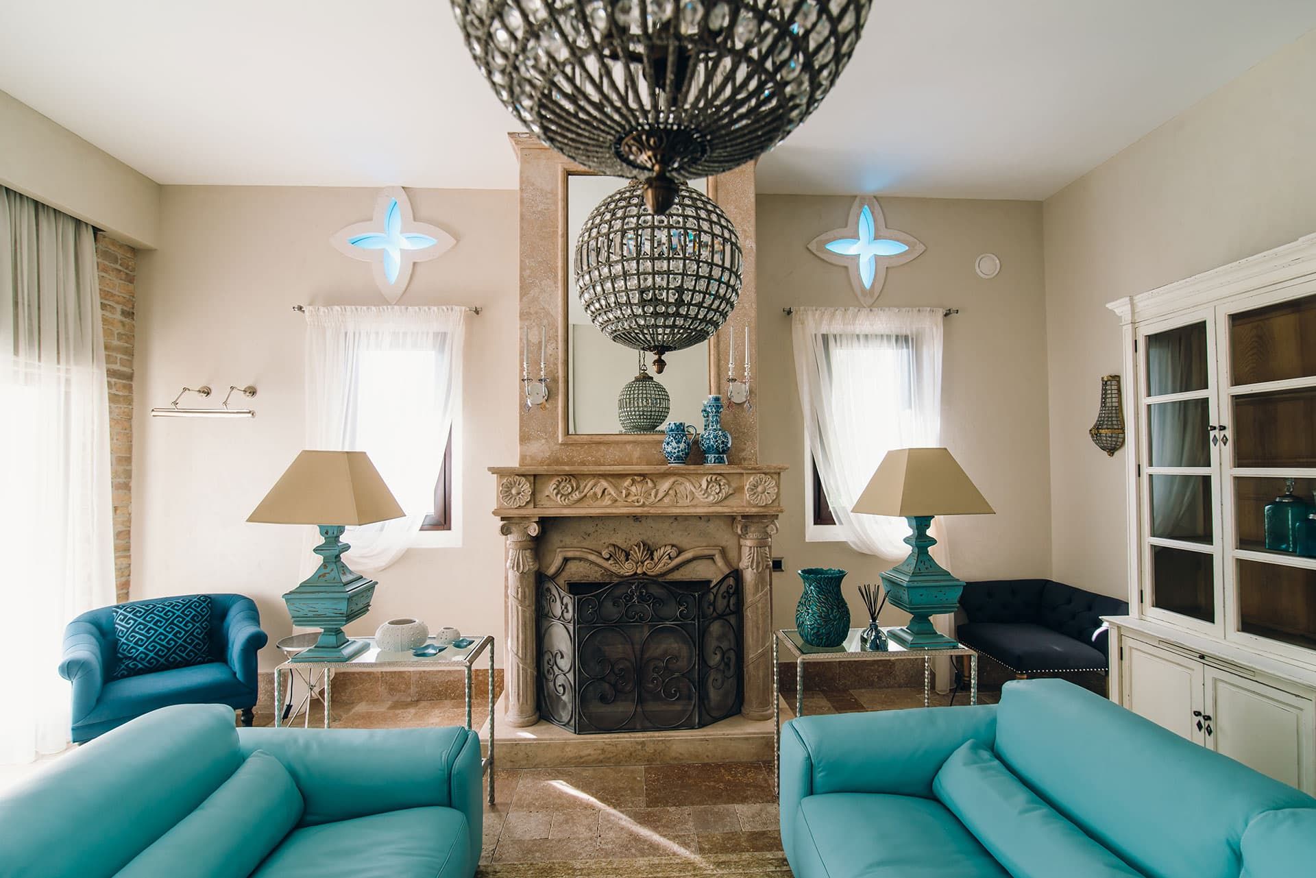 Luxurious living room with a fireplace and turquoise furniture in a villa in Reževići, Montenegro. Classic interior with chandeliers.