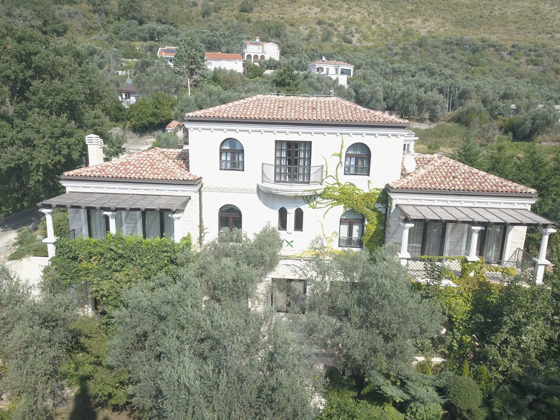 Two-story villa with a tiled roof and terraces surrounded by olive trees, Reževići, Montenegro.