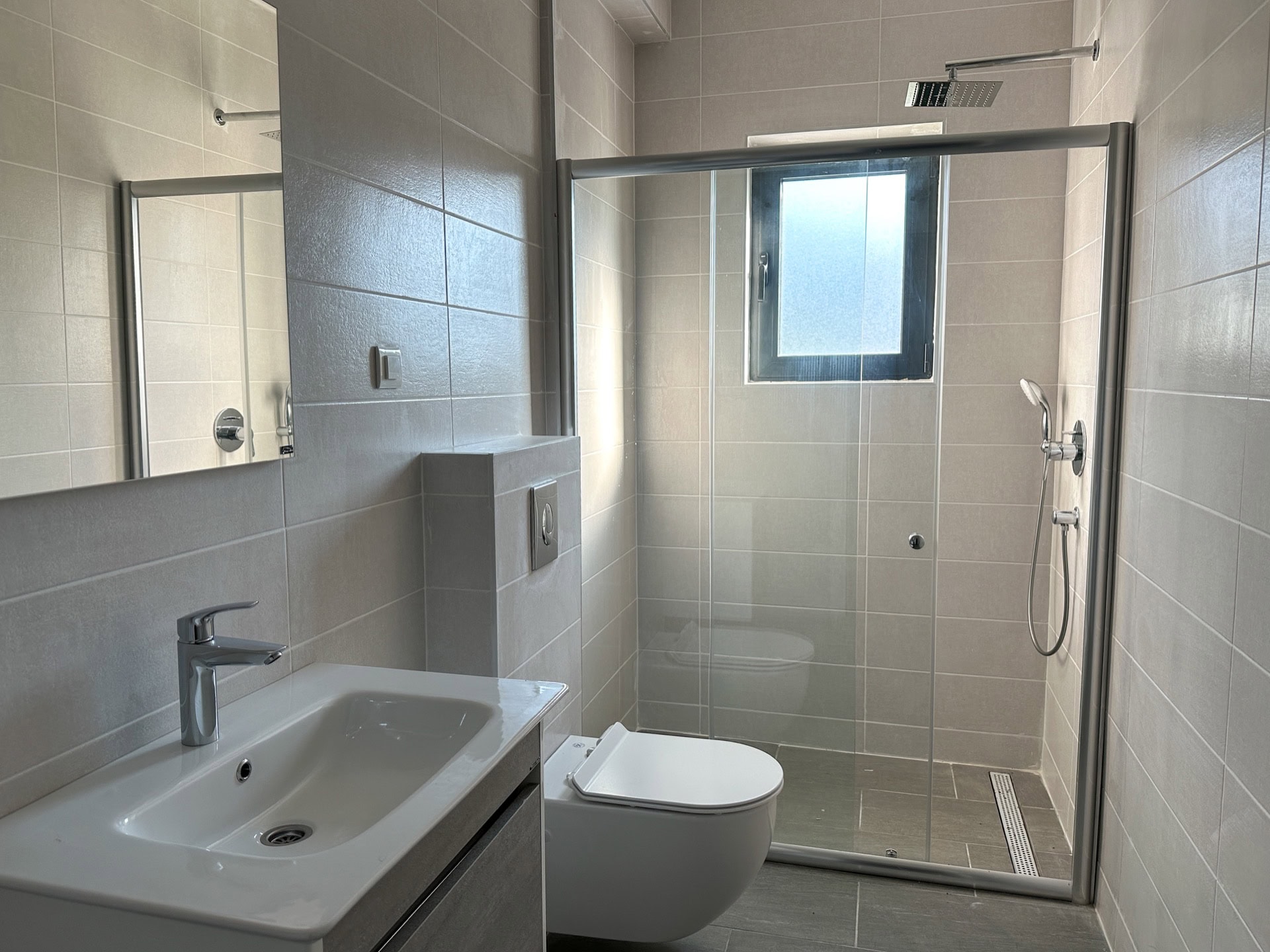 Modern bathroom with a shower cabin and light-colored tiles in an apartment, Becici, Montenegro.