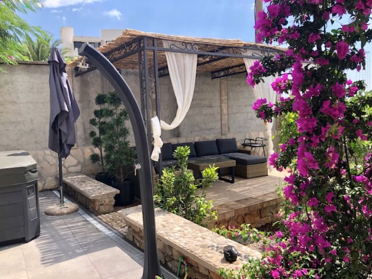 Cozy villa terrace in Krimovica, Montenegro: a gazebo with soft seating, stone finishes, and blooming bougainvillea.