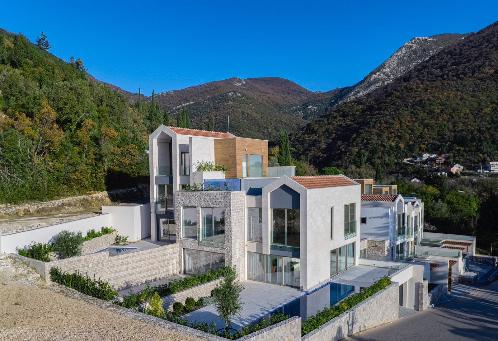 Modern villas with panoramic windows, terraces, and pools surrounded by mountains, residential complex in Tivat, Montenegro.