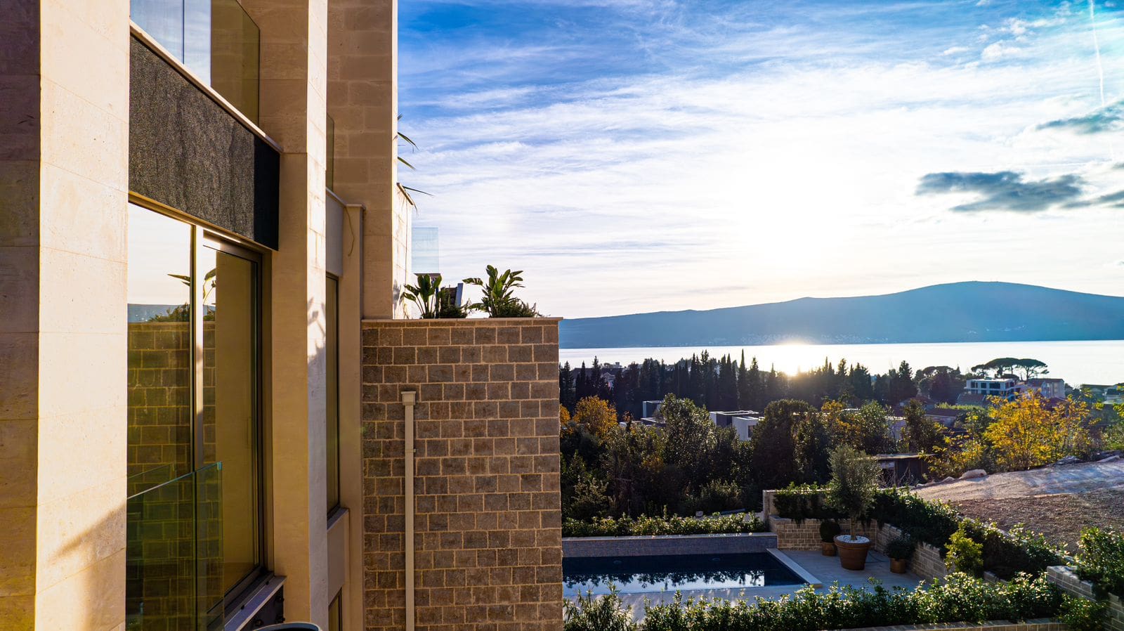 Modern villa in Tivat, Montenegro: pool view, stone facade finish, and panoramic views of the sea and mountains.