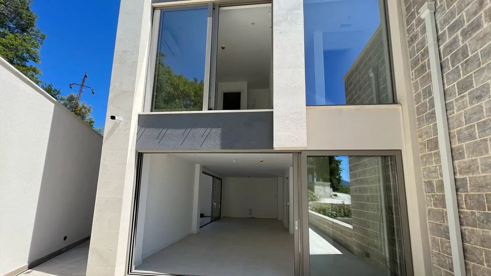 Modern villa with panoramic windows and stone facade cladding in Tivat, Montenegro. Exterior view of the residential complex.