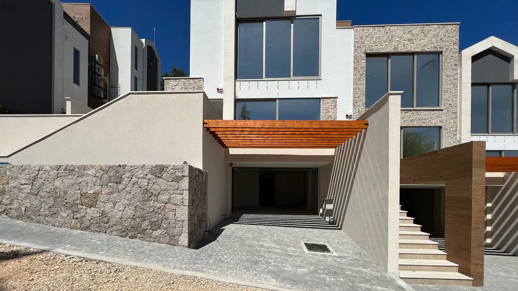 Modern villa in Tivat, Montenegro: stone-clad facade, panoramic windows, and covered parking space.