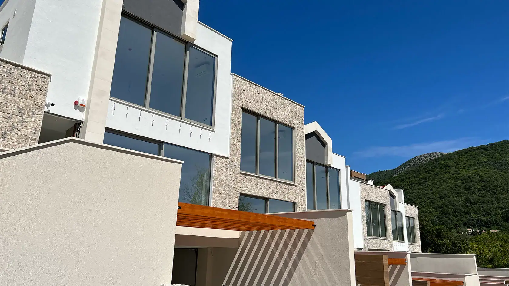 Modern townhouses with panoramic windows and stone facade cladding in Tivat, Montenegro.