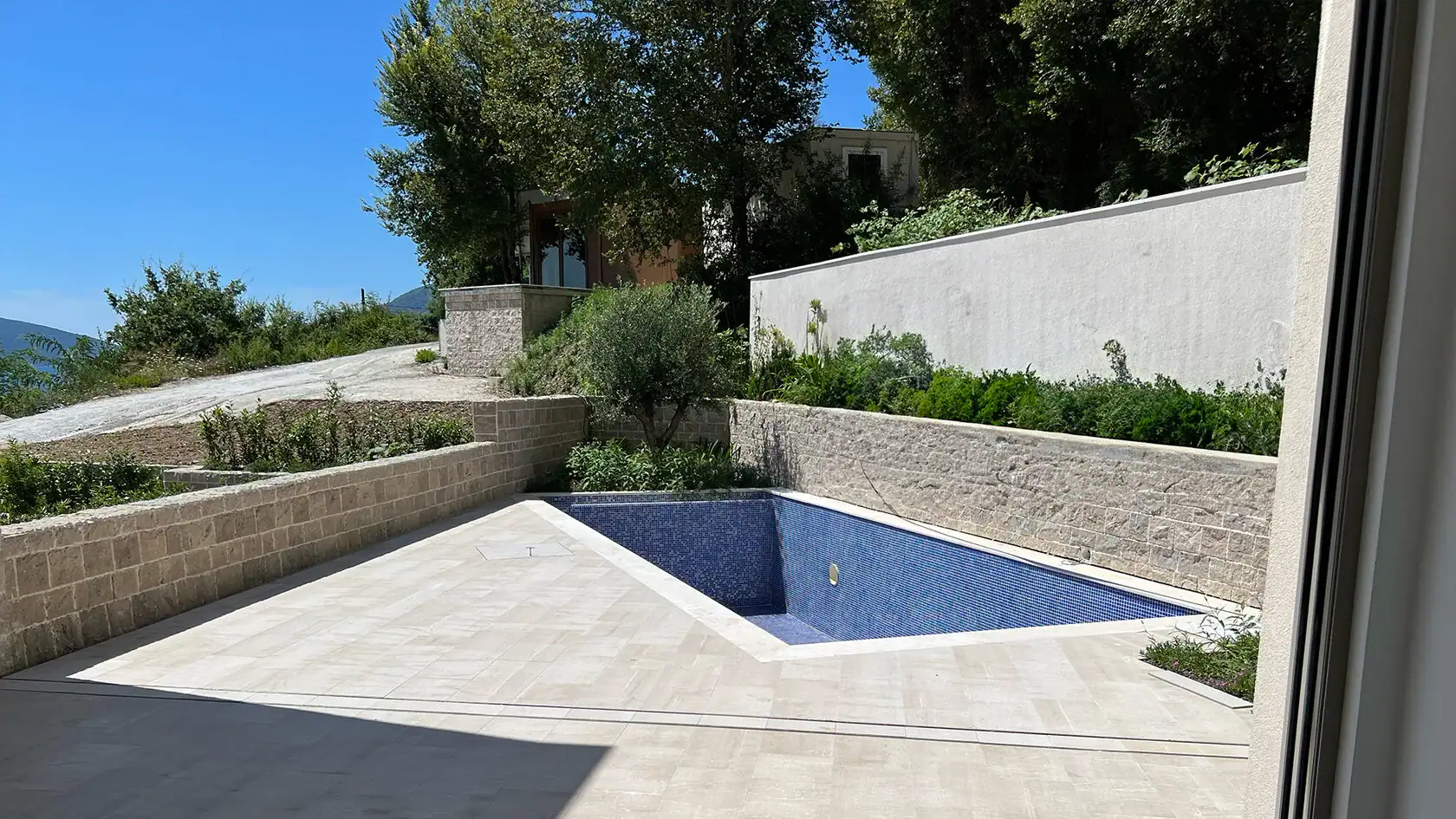 Outdoor pool with blue mosaic and stone terrace in a residential complex in Tivat, Montenegro.