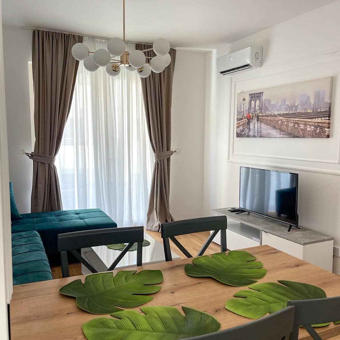 Living room in an apartment in Bečići, Montenegro: modern furniture, an emerald sofa, a dining table, and a stylish interior.