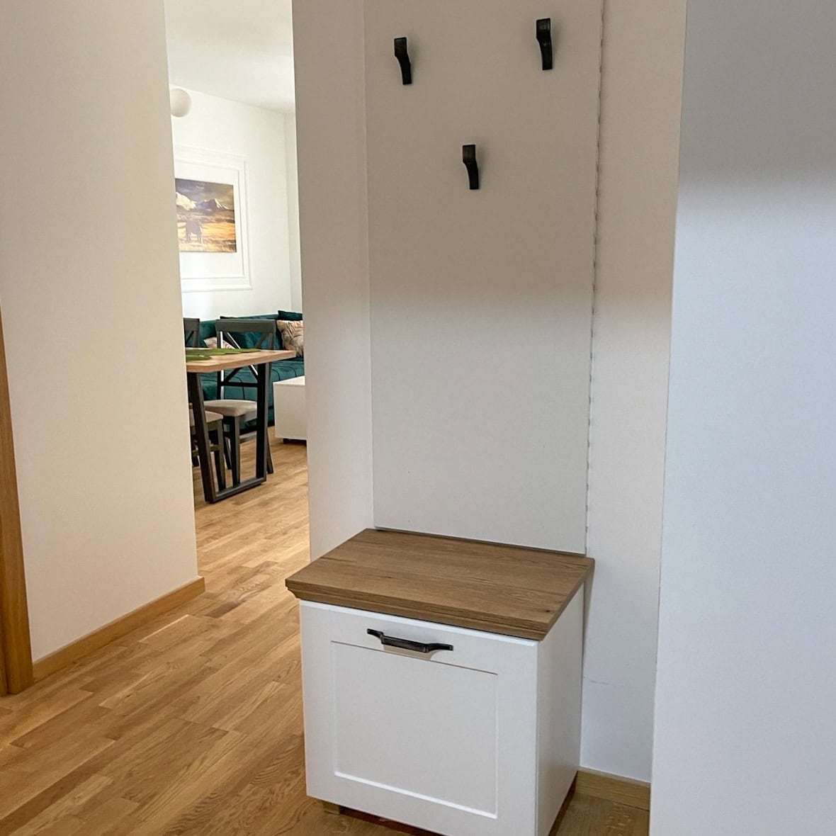 Hallway with a white cabinet and coat rack in a modern apartment, Becici, Montenegro. View of the living room with dining area.